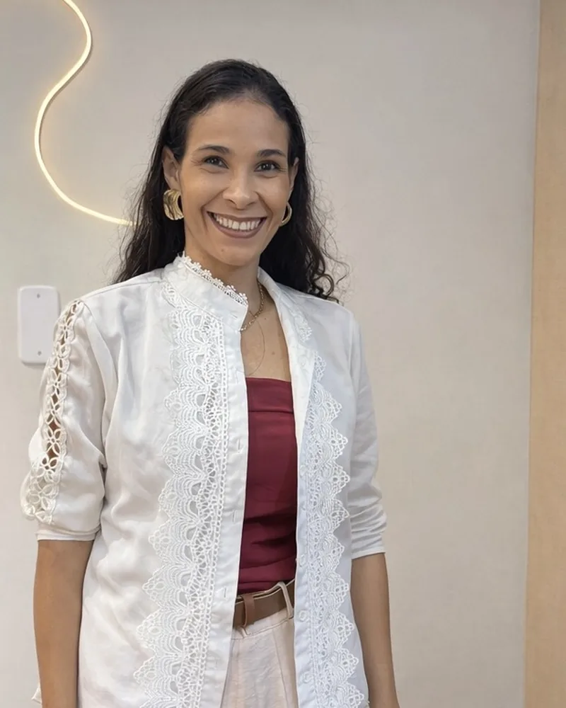 Isabela, esteticista responsável pela Békara, sorrindo em pé na sala de atendimento